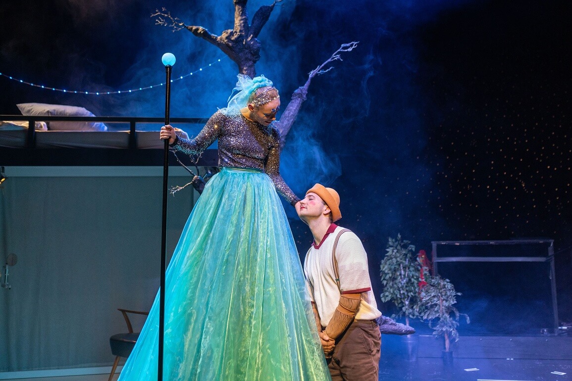 © Sofia Schomko Eine sehr große Frau mit einem langen blauen Rock und einem Zauberstab mit einer blauen Kugel obenauf schaut nach unten auf einen Jungen, der sich mit seiner Wange in ihre ihm entgegengestreckte Hand schmiegt